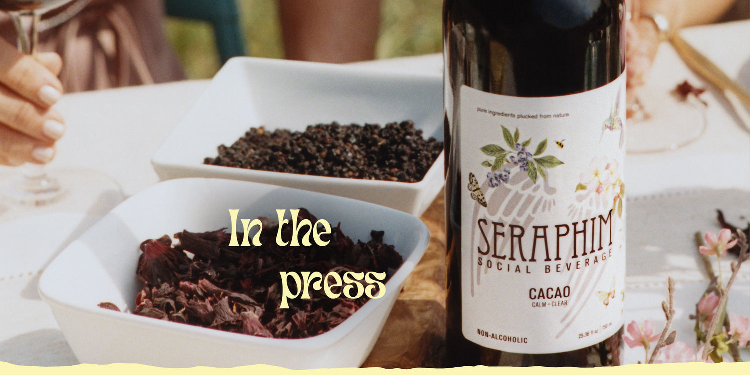 Image of a bottle of Seraphim Social Beverage, a non-alcoholic social wine alternative made from pure ingredient with ingredients on a table. Text reads: In the press